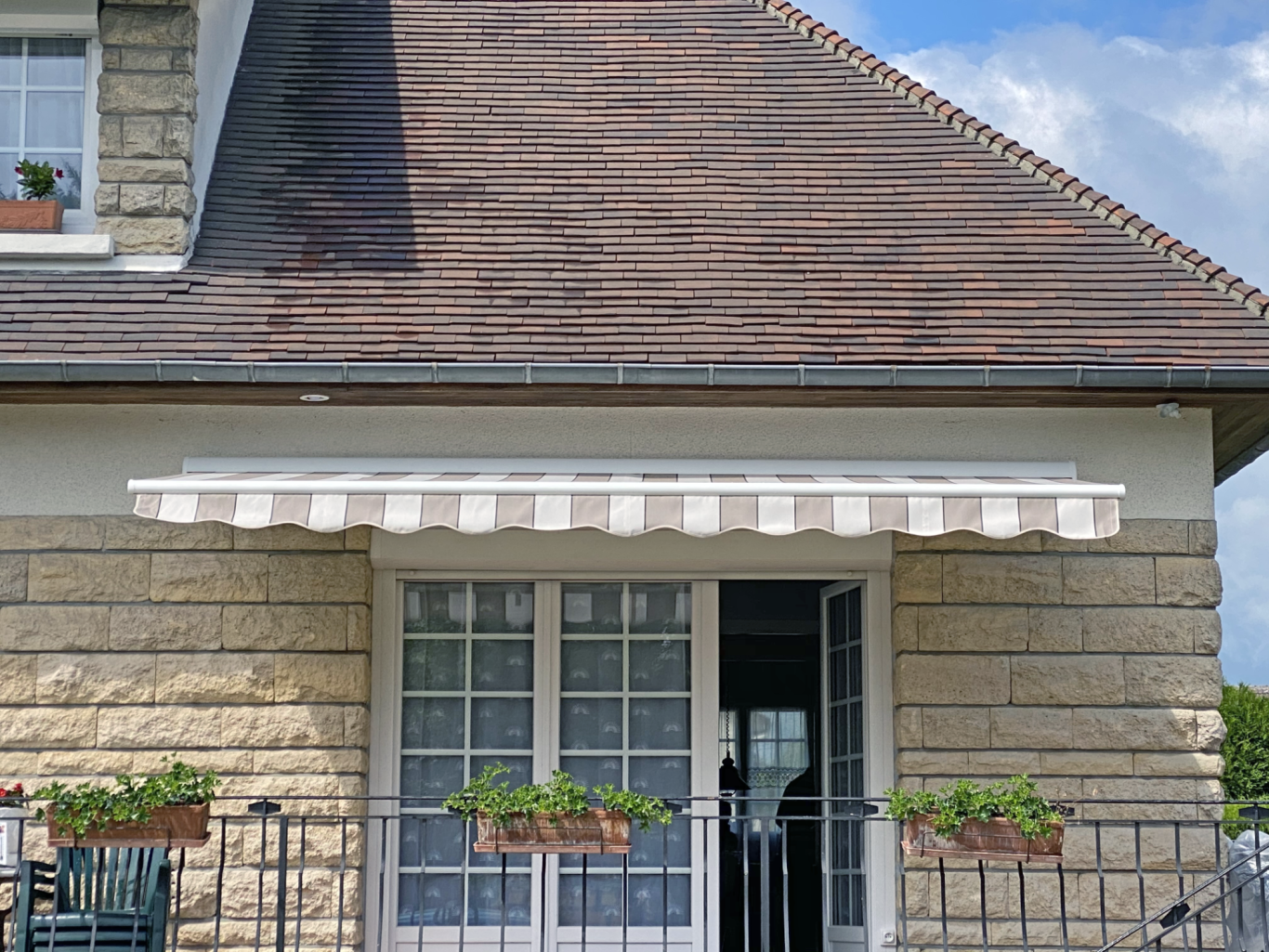 Façade d'une maison avec un auvent blanc et des jardinières fleuries.