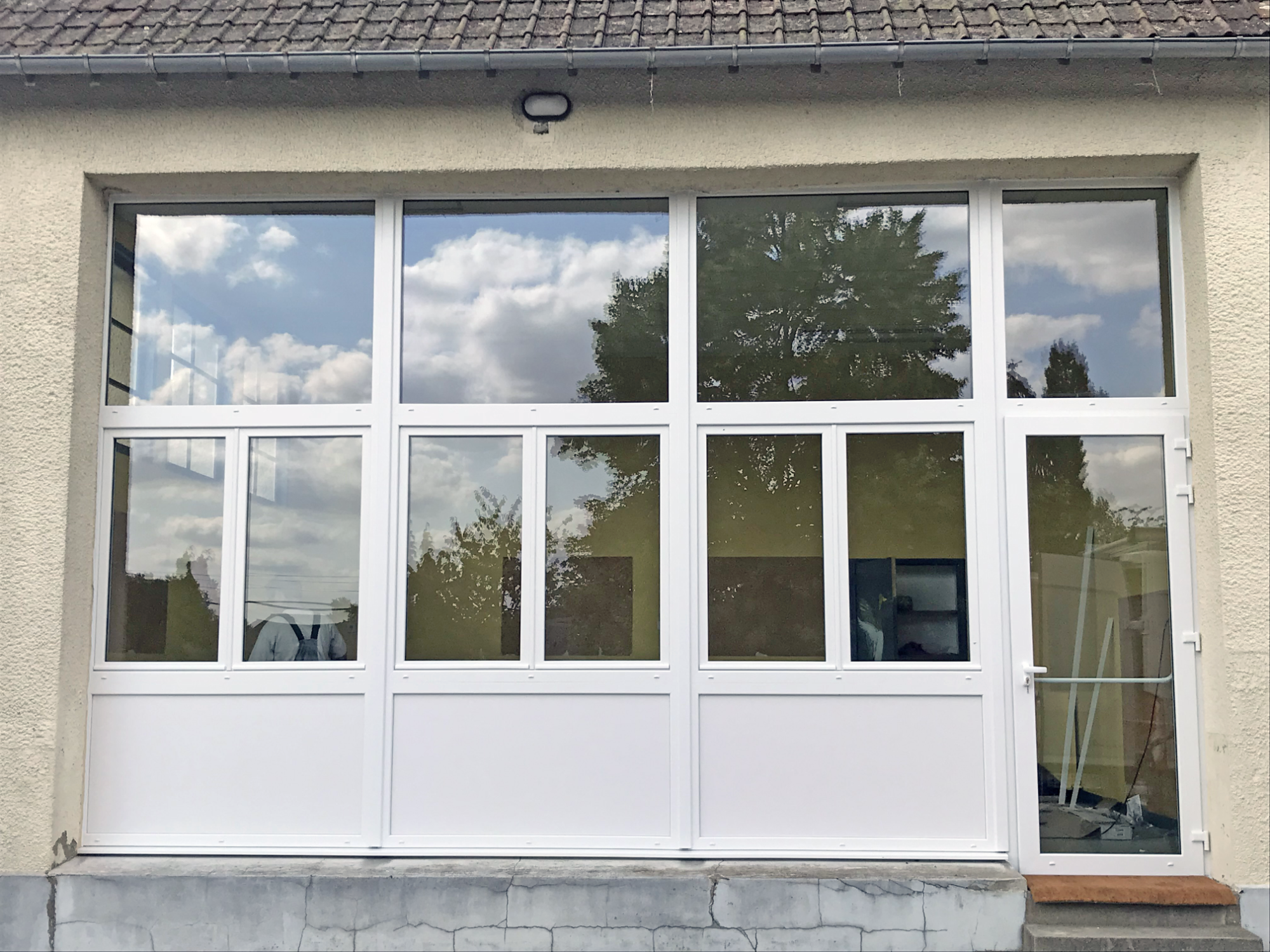Vue d'une façade de bâtiment avec plusieurs fenêtres blanches et un ciel nuageux.