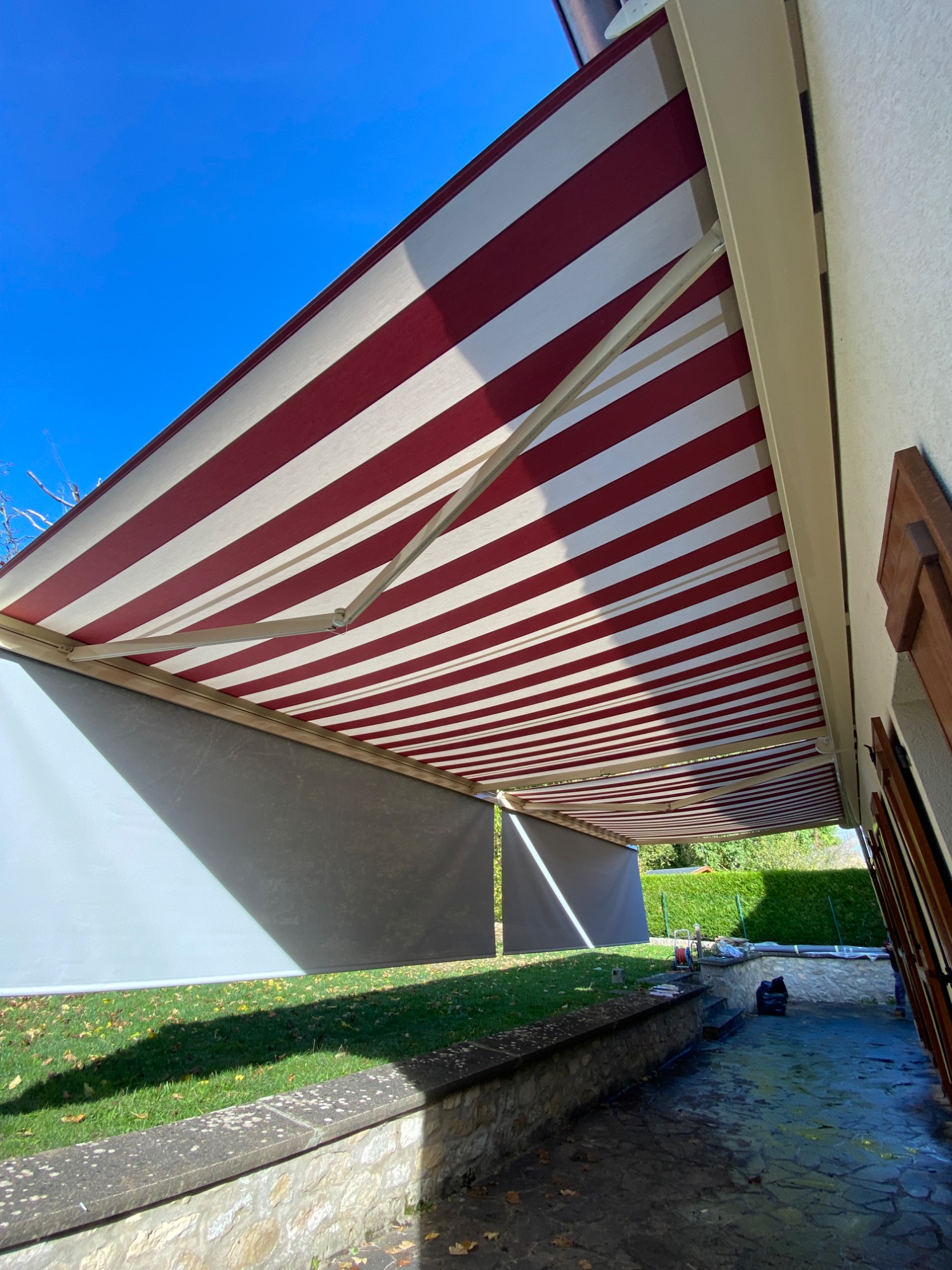 Auvent rayé rouge et blanc, vue sous un angle, avec ciel bleu en arrière-plan.