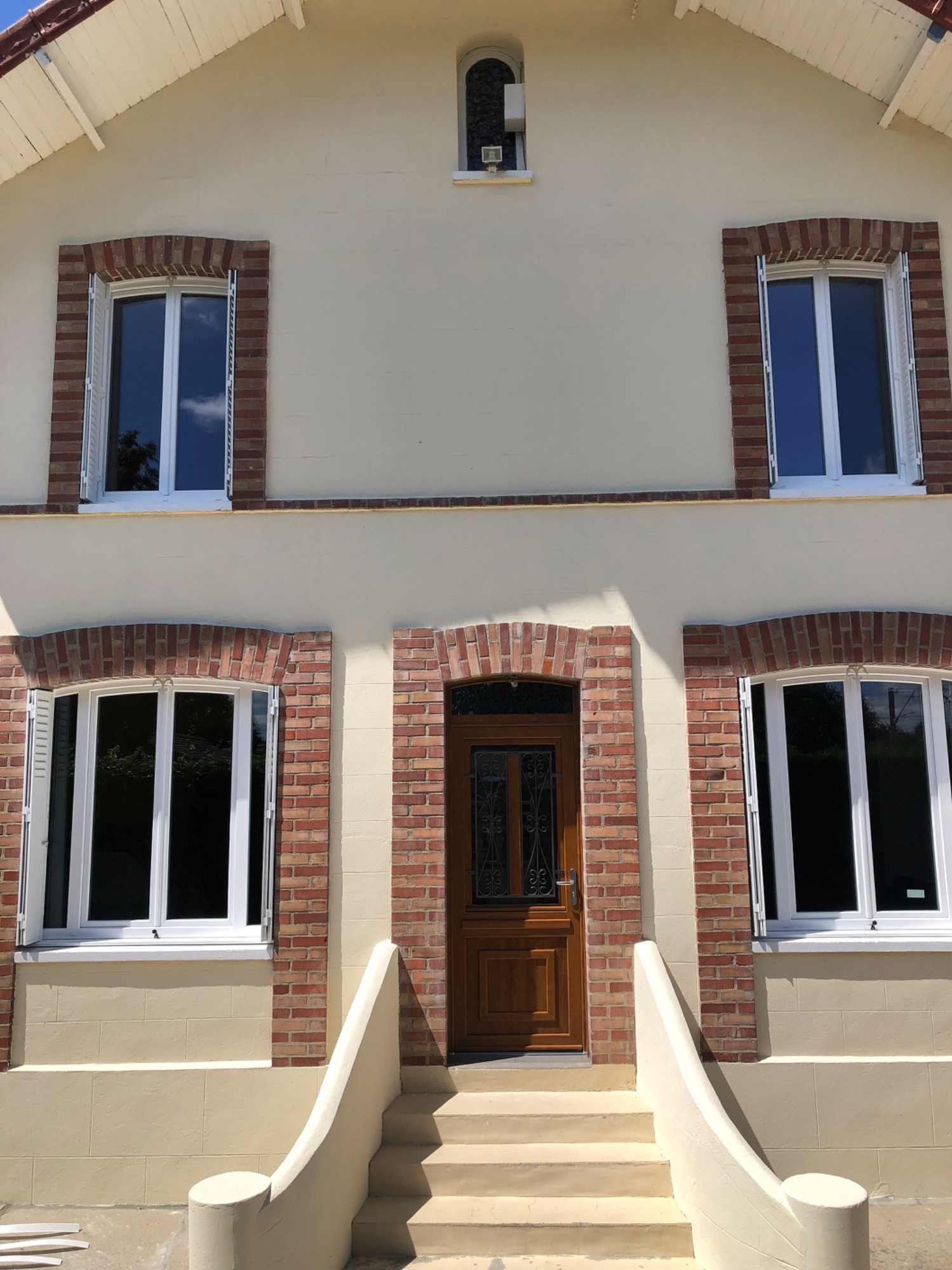 Façade d'une maison avec des fenêtres à meneaux et une porte en bois.