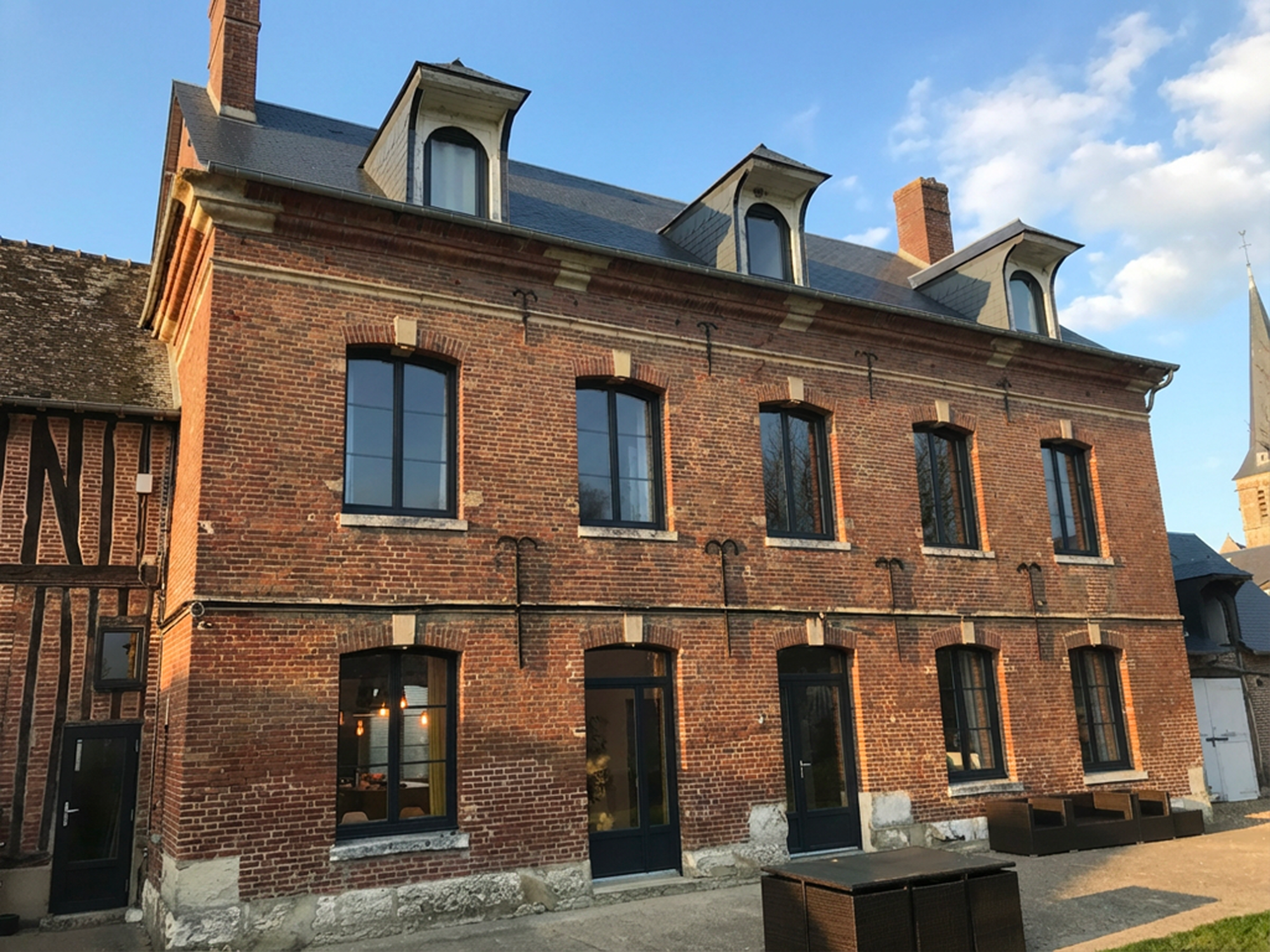 Bâtiment en brique rouge avec fenêtres et toits à pignon sous un ciel partiellement nuageux.