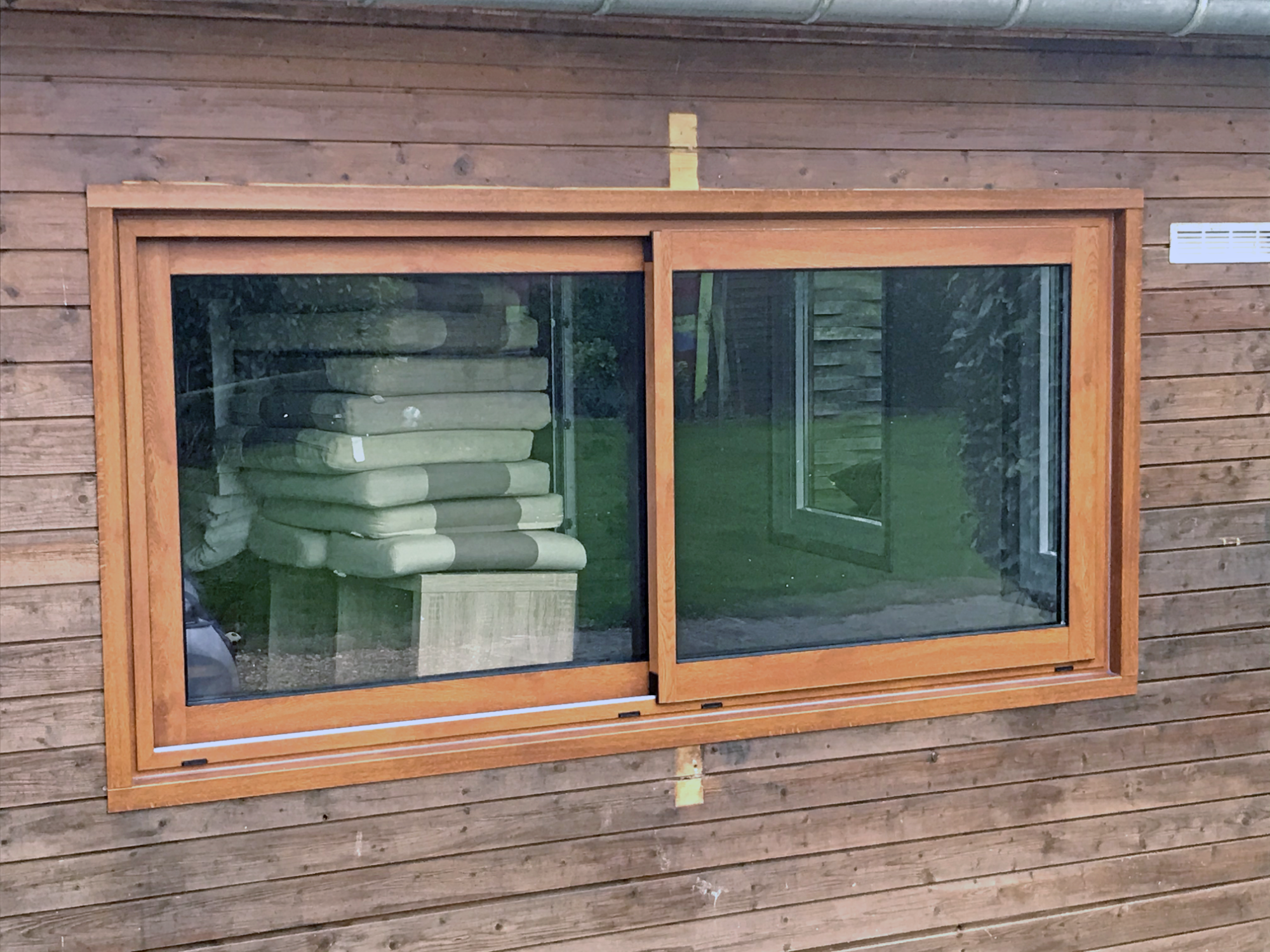 Fenêtre en bois avec deux volets, vue sur des empilements de matériaux à l'intérieur.