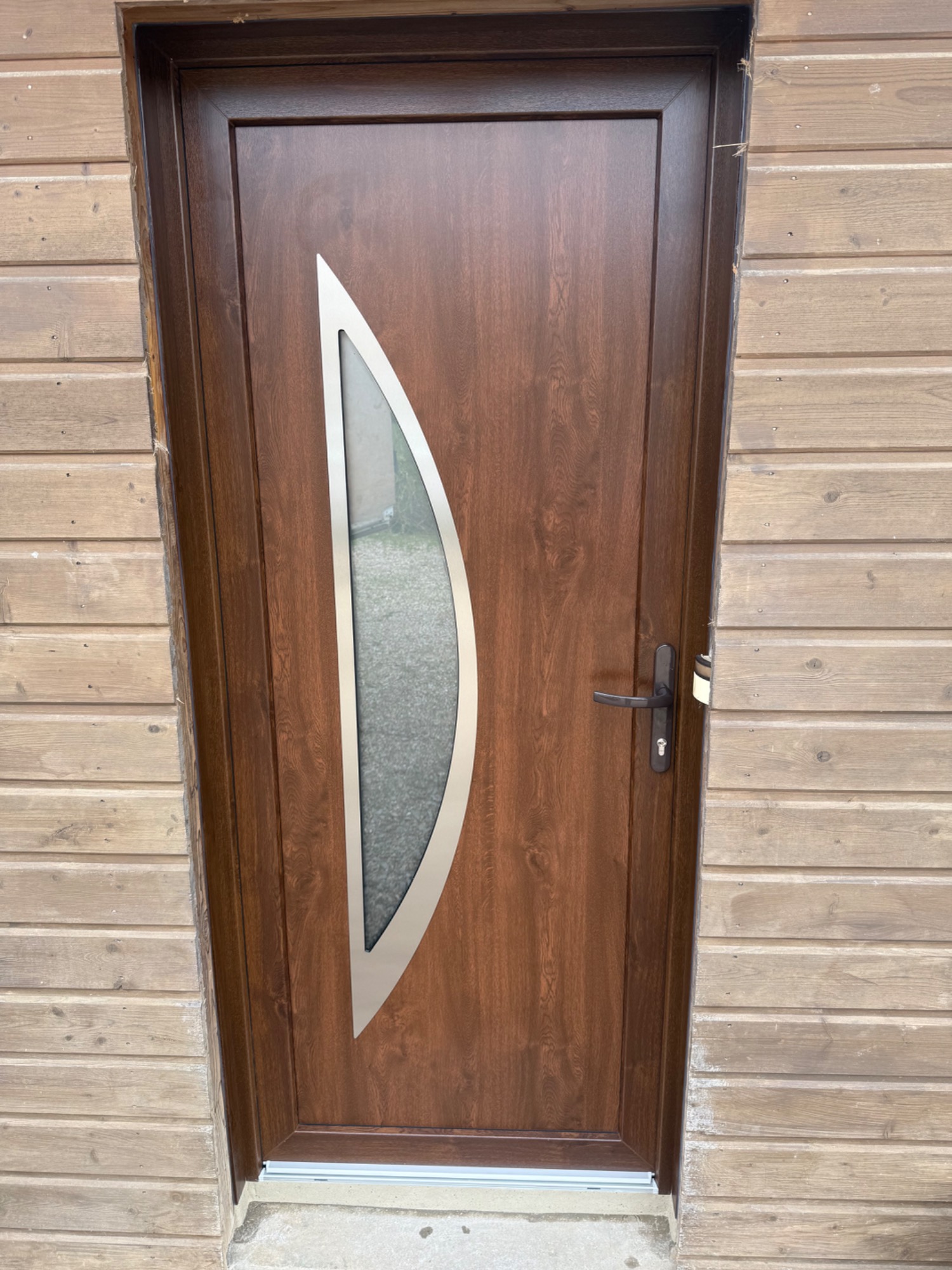 Porte en bois avec un va-et-vient en verre courbé.