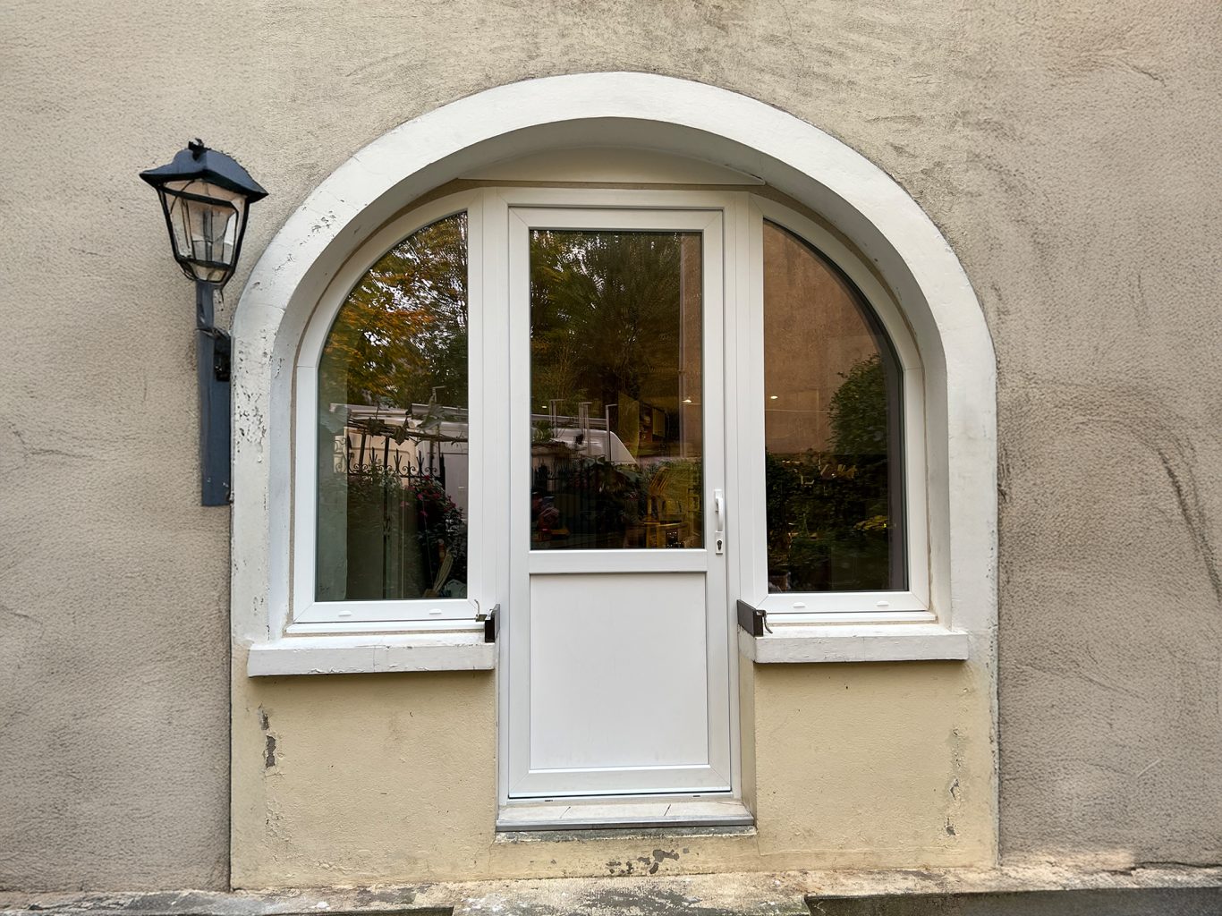 Fenêtre blanche à arc avec une petite porte en bas et un lampadaire à côté.