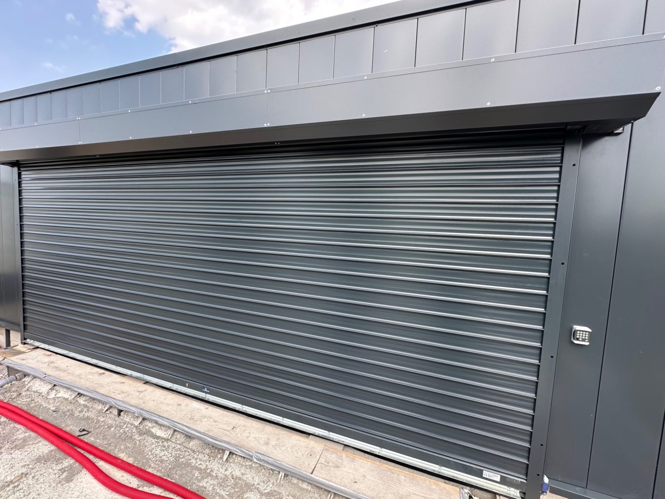 Rideau métallique gris fermé sur un mur de bâtiment moderne.