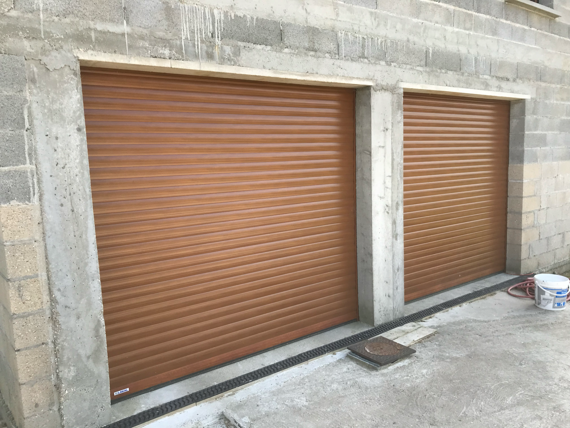 Deux volets roulants marron installés dans un mur en béton.